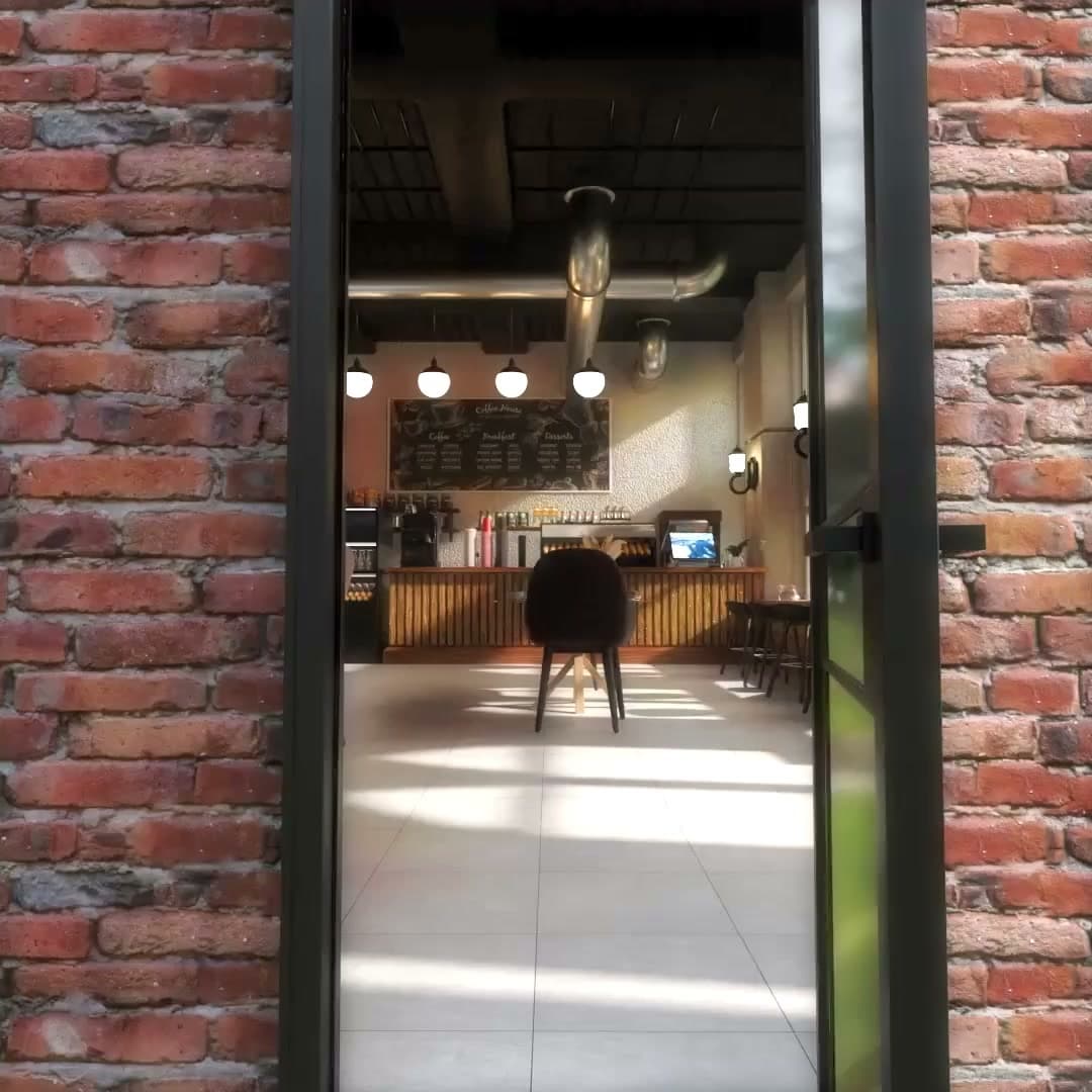 Loistopixel's 3D cafe render showing the counter and sunlit floor through a brick-framed entrance